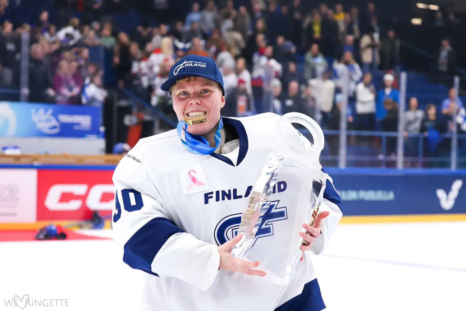Maria kultamitali hampaissa ja MM-pokaali kädessään Suomen ringettemaajoukkueen pelipaidassa
